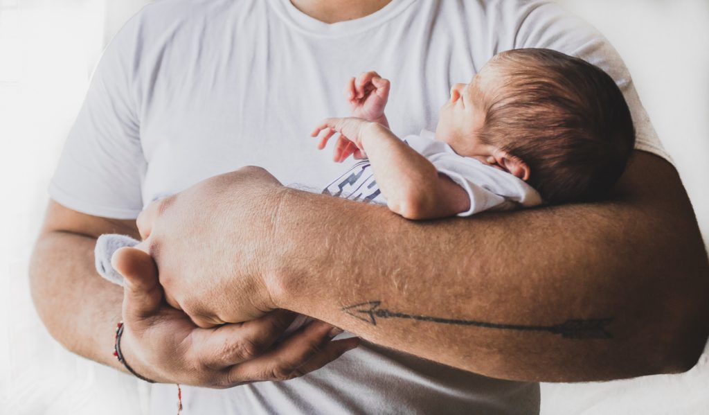 father carrying newborn