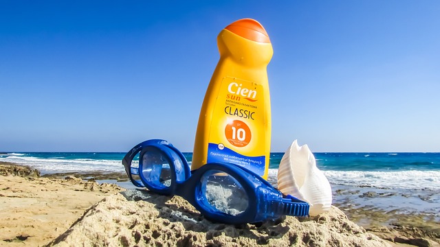 Sunscreen lotion with swimming goggles on the beach