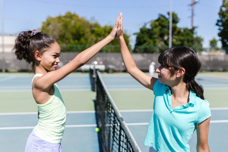 Girls at the tennis court giving each other a high five