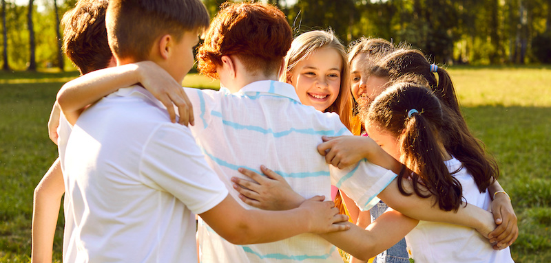 group of kids happy & hugging each other outside