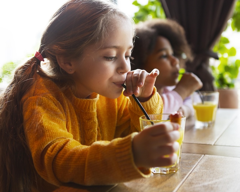 2 girls drinking juice at a table